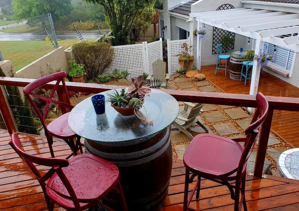 Wooden deck with red chairs and barrel table overlooking garden