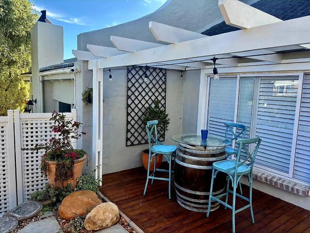 Covered outdoor deck with barrel table, blue chairs, pergola shade structure