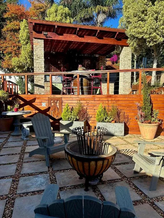 Outdoor patio with fire bowl, wooden deck, and stone cottage pergola