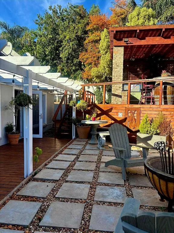 Wooden deck with patio seating, pergola, and colorful autumn garden backdrop