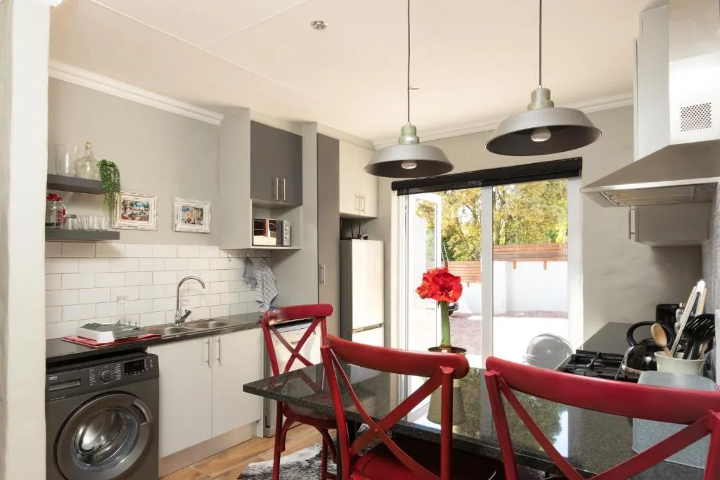 Modern kitchen with white cabinetry, stove, and red dining chairs