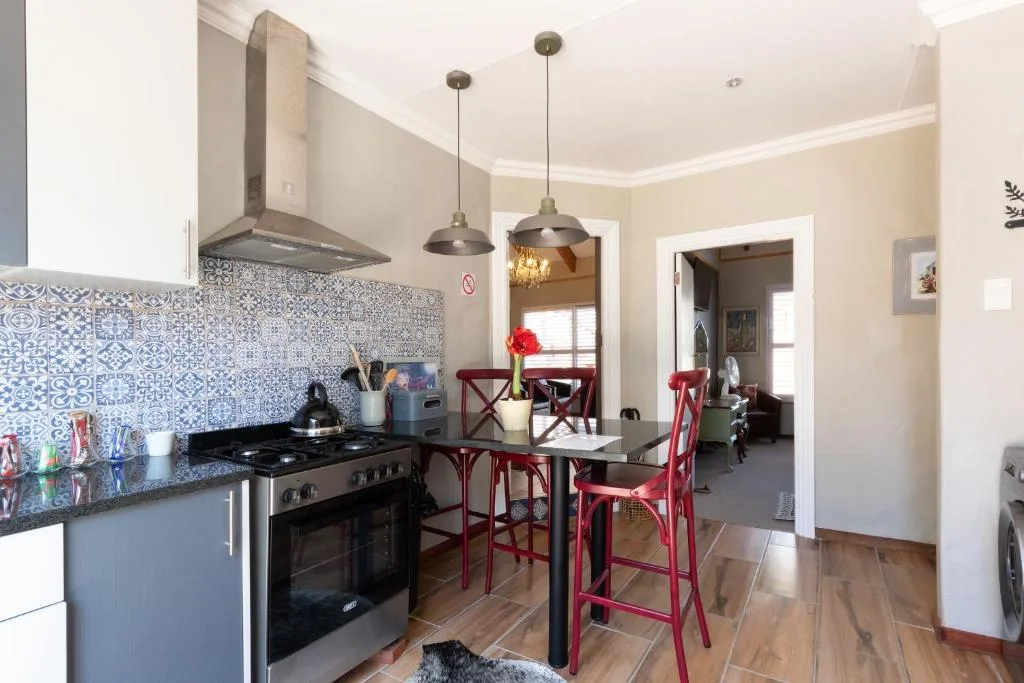 Modern kitchen with blue patterned backsplash, black stove, and dining counter with red chairs