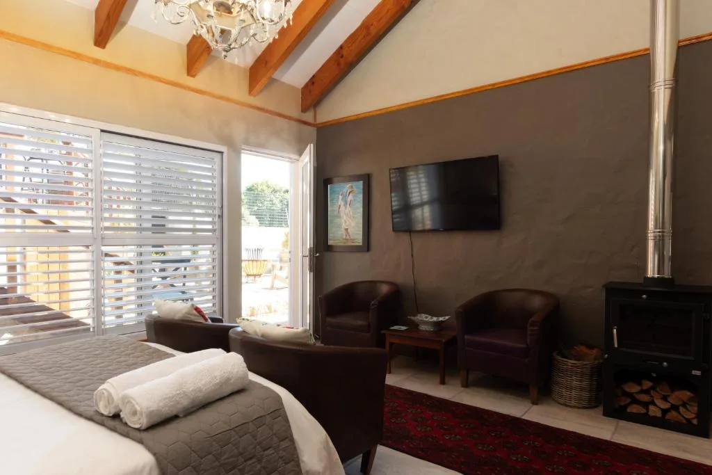 Spacious lounge with dark leather seating, wall-mounted TV, and deck access