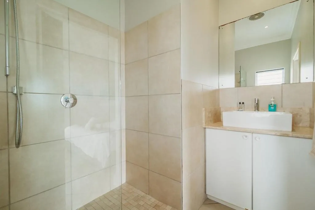 Modern bathroom with walk-in shower, vanity sink, and large mirror