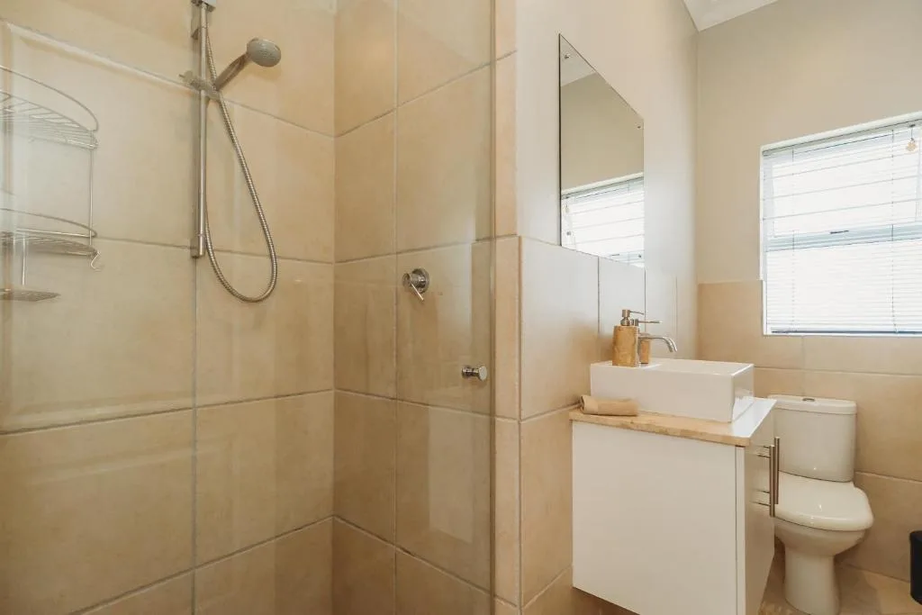 Modern bathroom with walk-in shower, white basin vanity, and toilet