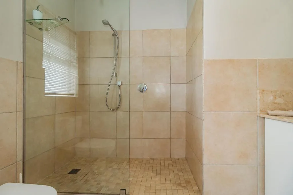 Modern walk-in shower with glass enclosure and cream tile walls