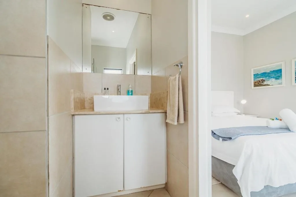 Modern bathroom with white vanity sink, large mirror, and rainfall showerhead