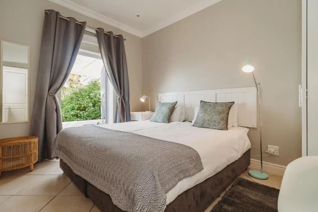 Spacious bedroom with queen bed, grey curtains, garden view through doors