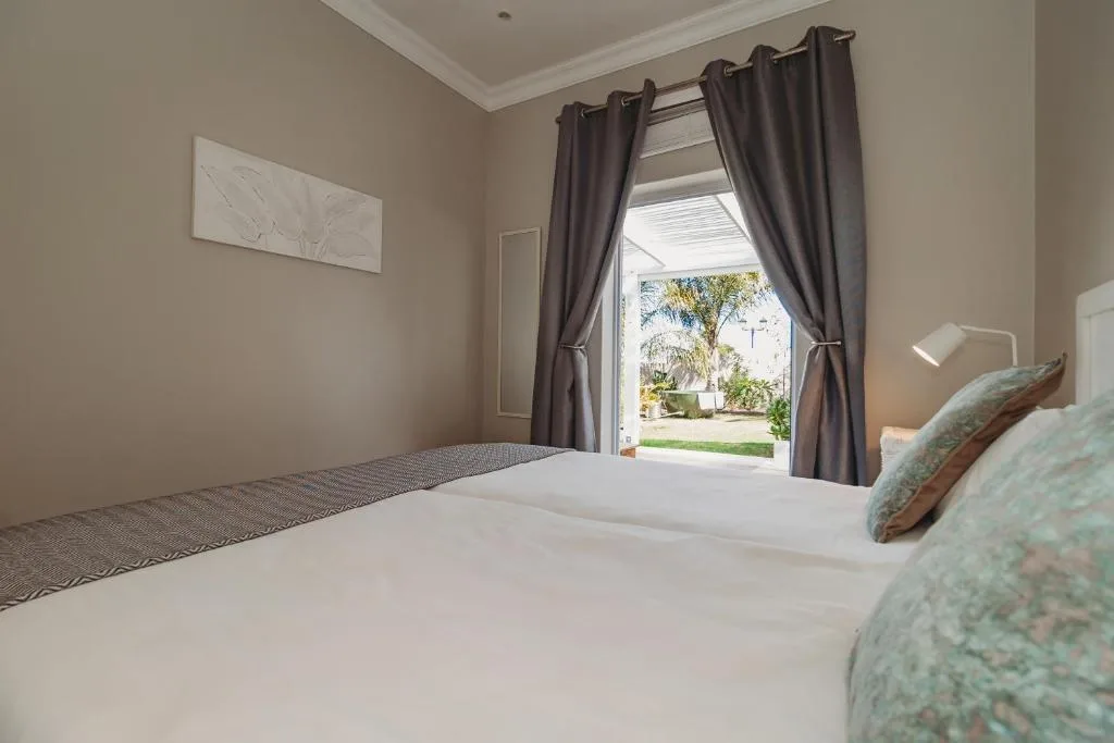 Bright bedroom with double bed and garden views through open doors