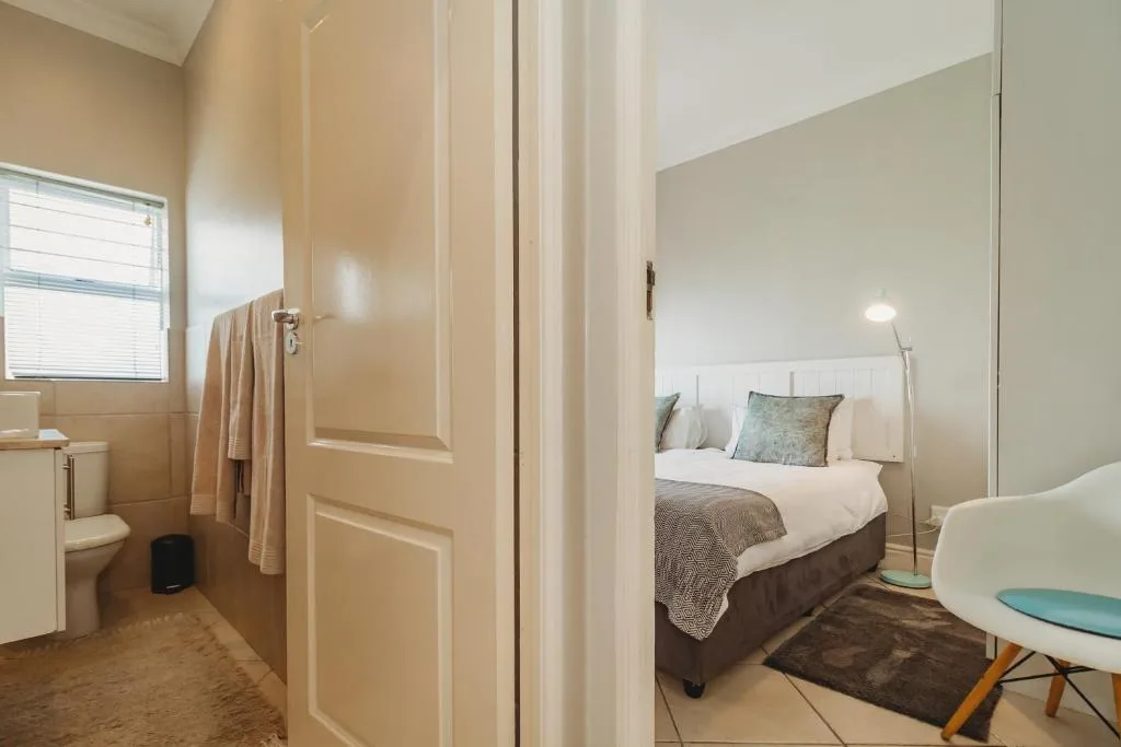 Modern bedroom with double bed, white headboard, and en-suite bathroom access