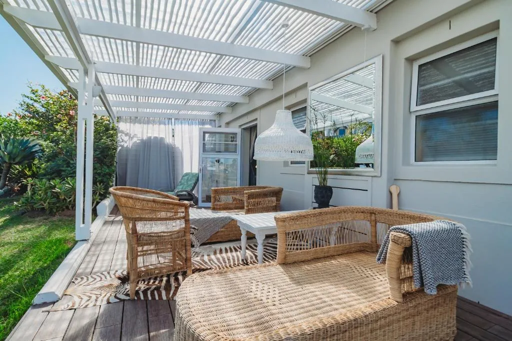 Covered patio with wicker furniture, pendant lighting, and garden views