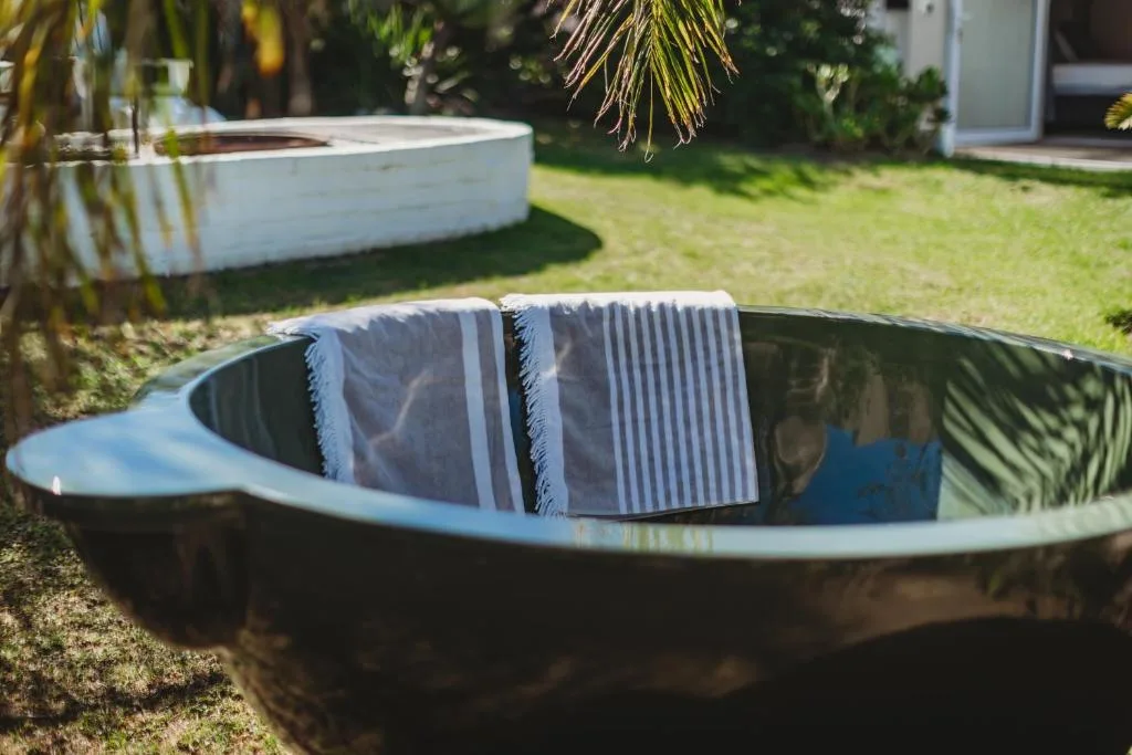 Outdoor hot tub with towels, set in lush green garden grounds