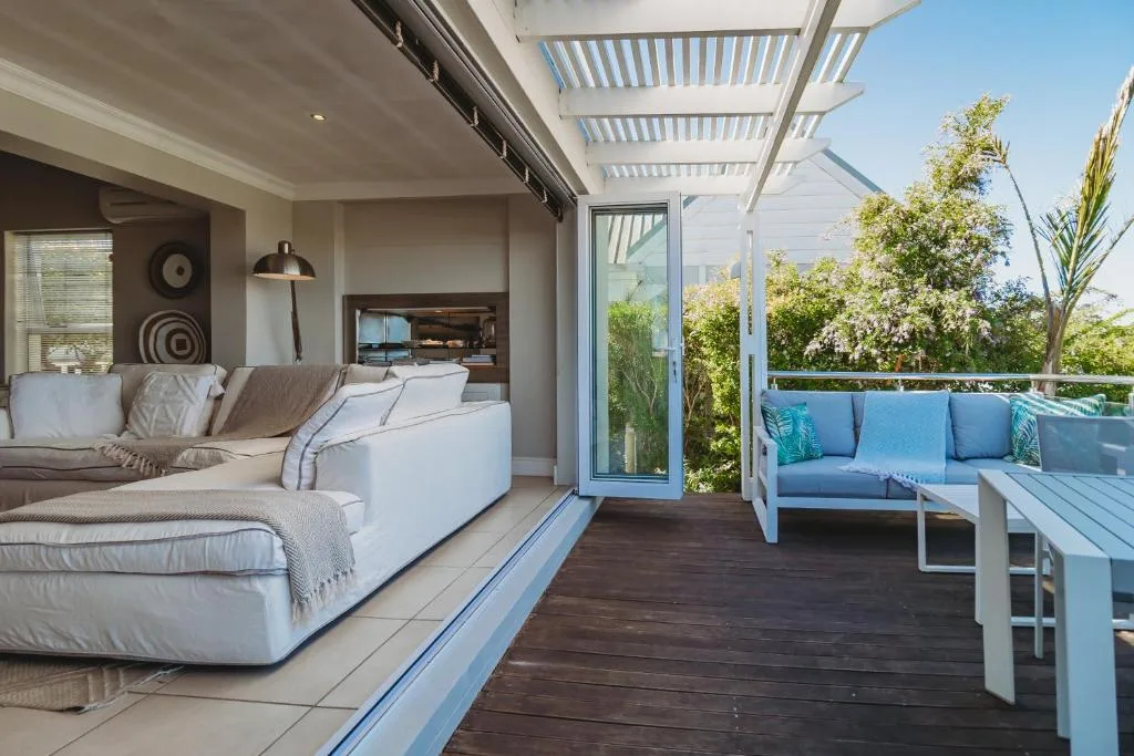 Modern deck with blue seating, pergola, and garden views overlooking lounge