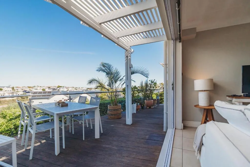 Spacious deck with pergola, dining table, and lagoon views