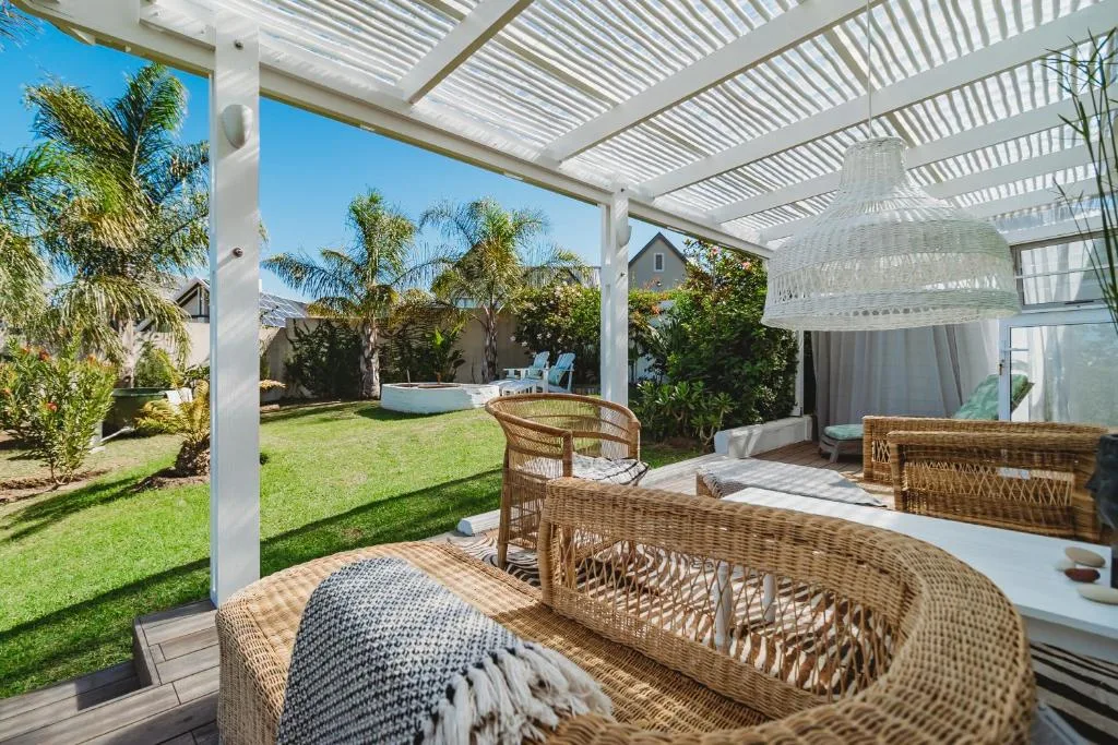 Covered outdoor patio with wicker seating overlooking manicured garden and lawn