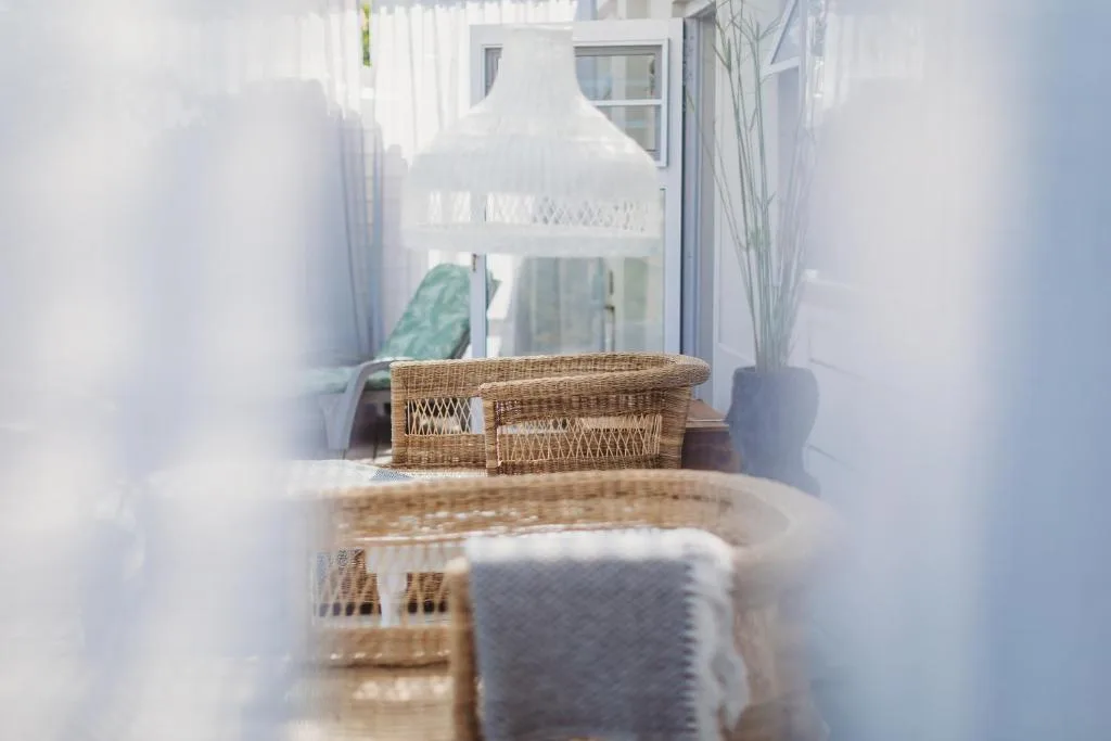 Wicker seating area on bright outdoor deck with white curtains
