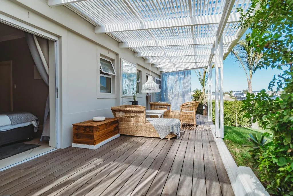 Covered deck with wicker seating, wooden flooring, and garden views