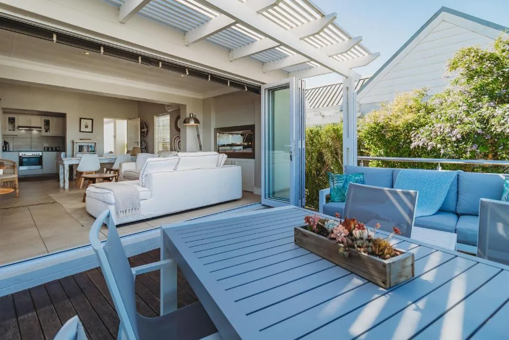 Spacious covered deck with blue furniture and ocean views from property