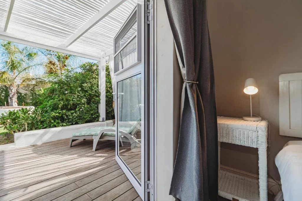 Wooden deck with sunlounger, polycarbonate roof, and garden views