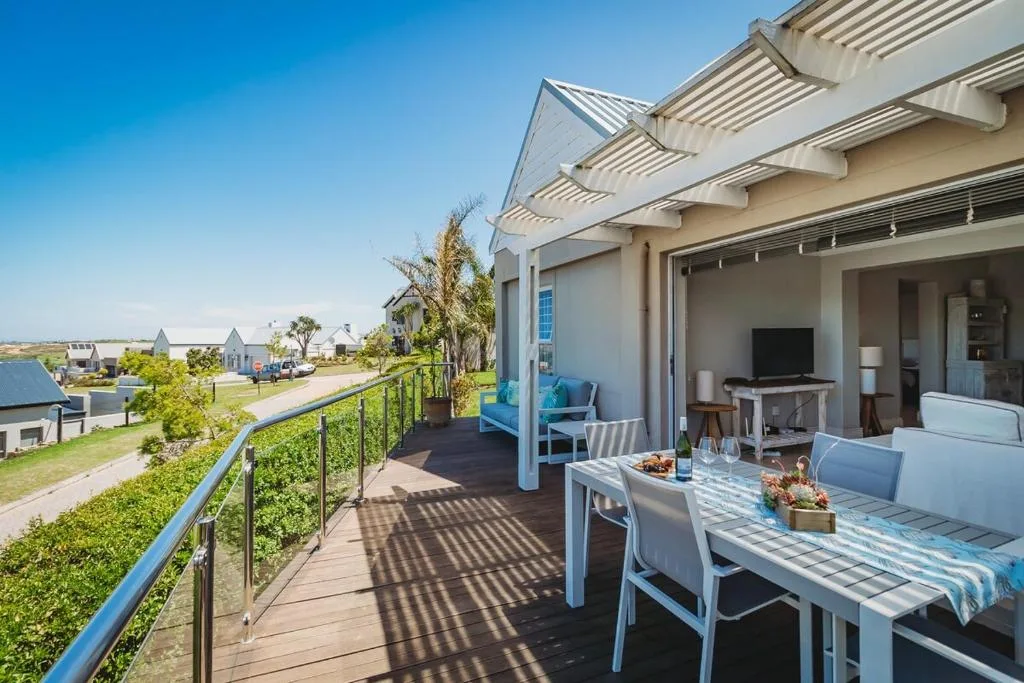 Spacious covered deck with dining table overlooking lagoon and golf estate