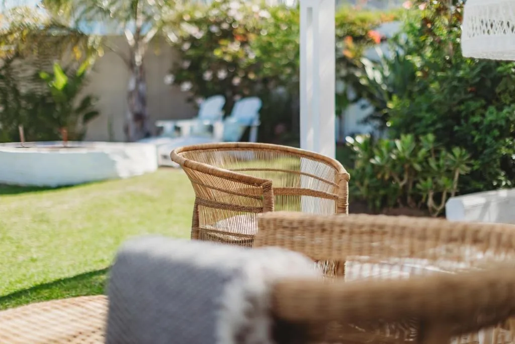 Woven rattan chairs on paved deck overlooking manicured garden and lawn