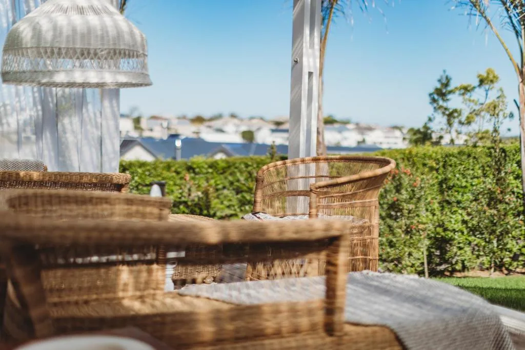 Outdoor seating area with wicker chairs overlooking lagoon and gardens