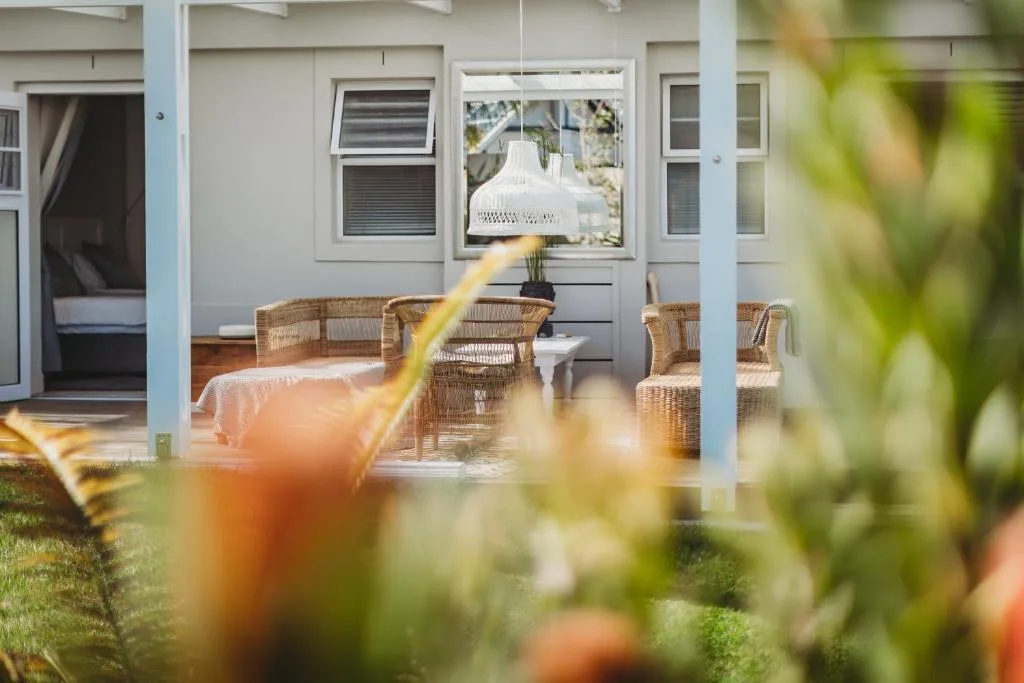 Covered patio with wicker chairs and white pendant lamp, garden view