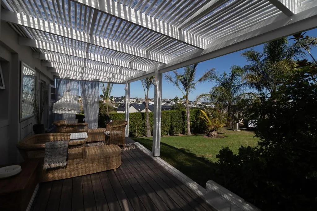 Covered patio with pergola, wicker furniture, and garden views