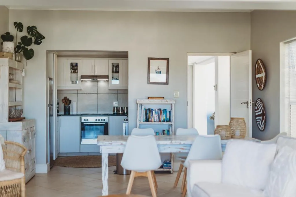 Open-plan dining area with white chairs and table, adjacent to kitchen