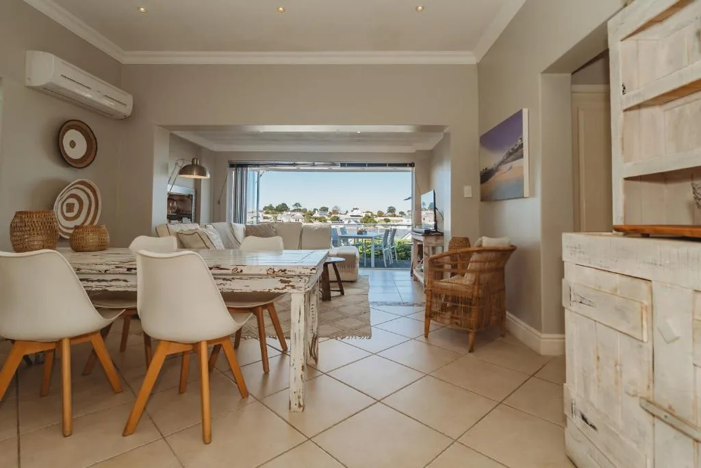 Spacious dining area with marble table and modern chairs overlooking town