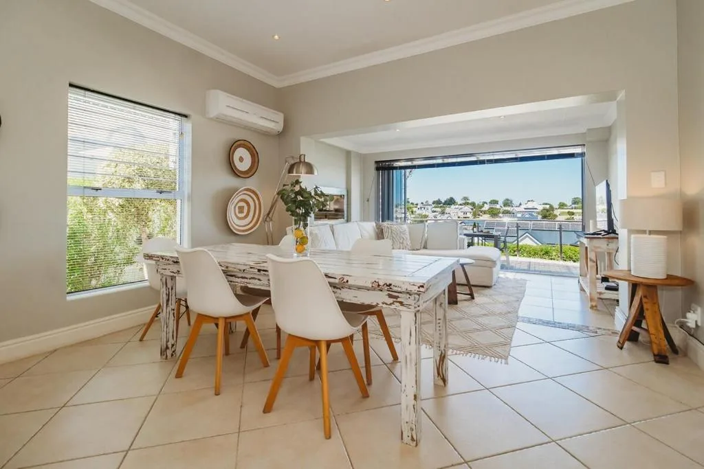 Spacious dining area with whitewashed table and cream chairs overlooking lagoon view