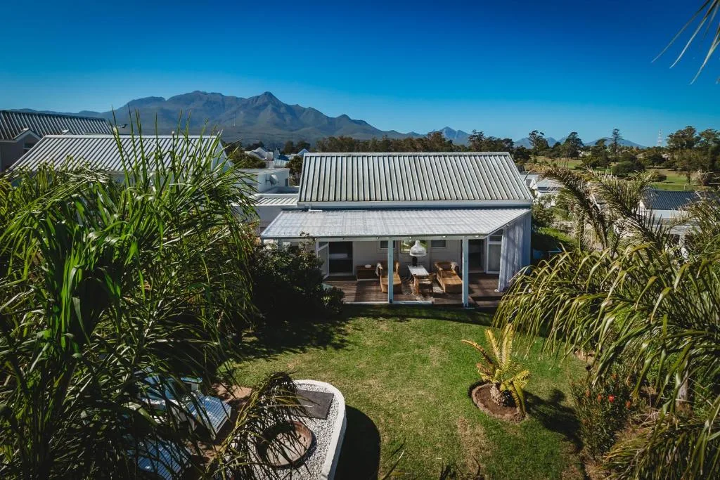 Modern white-roofed house with garden, mountains visible in distance