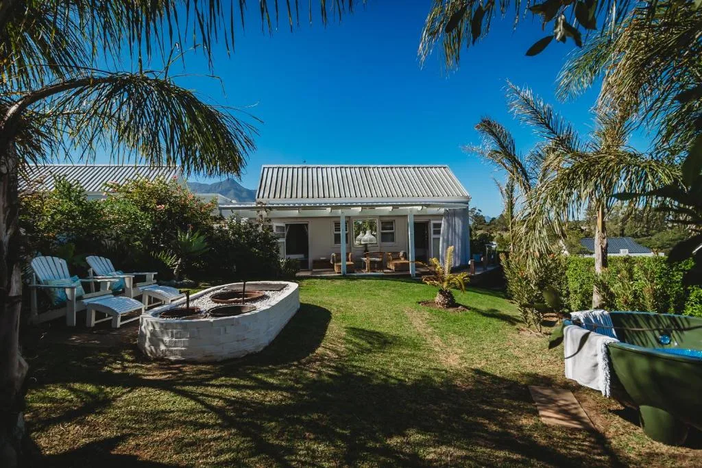 Charming cottage with metal roof, palm trees, garden seating, and fire pit