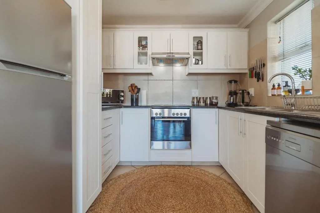 Modern white kitchen with stainless steel appliances and black countertops