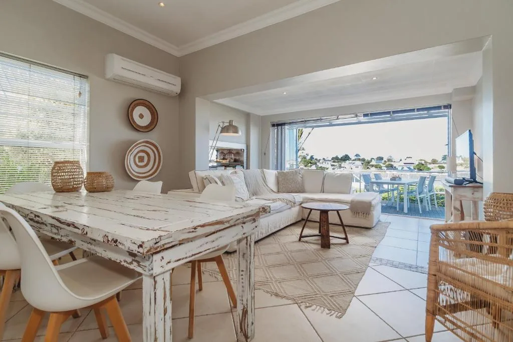 Open-plan living space with sofa, dining table, and scenic lagoon views