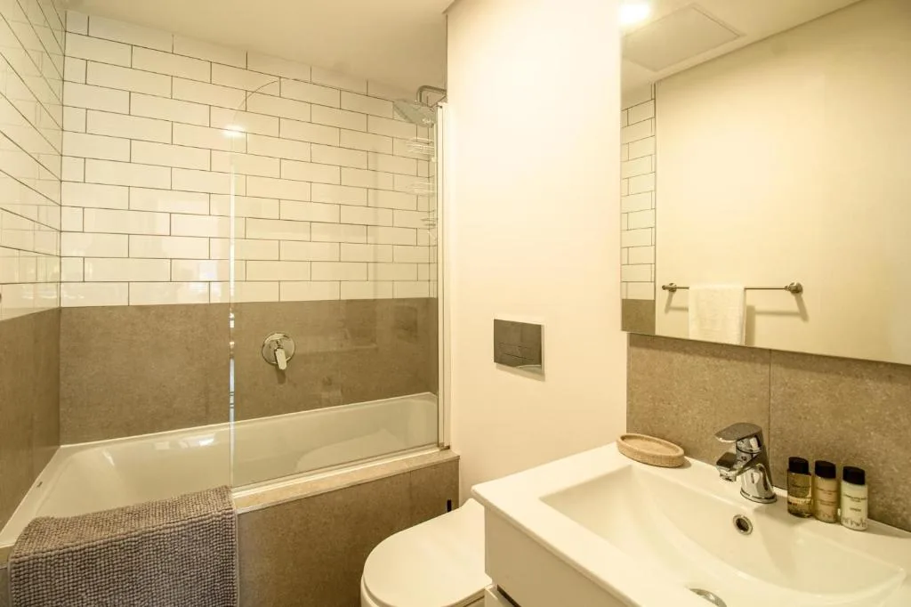 Modern bathroom with subway tile shower, white vanity sink, and toilet