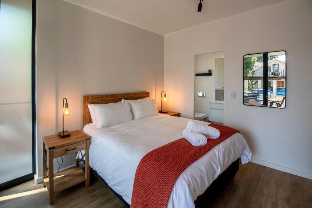 Modern bedroom with queen bed, white linens, red throw, and pendant lighting