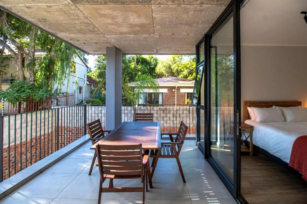 Covered patio with wooden dining table, chairs, and bedroom view