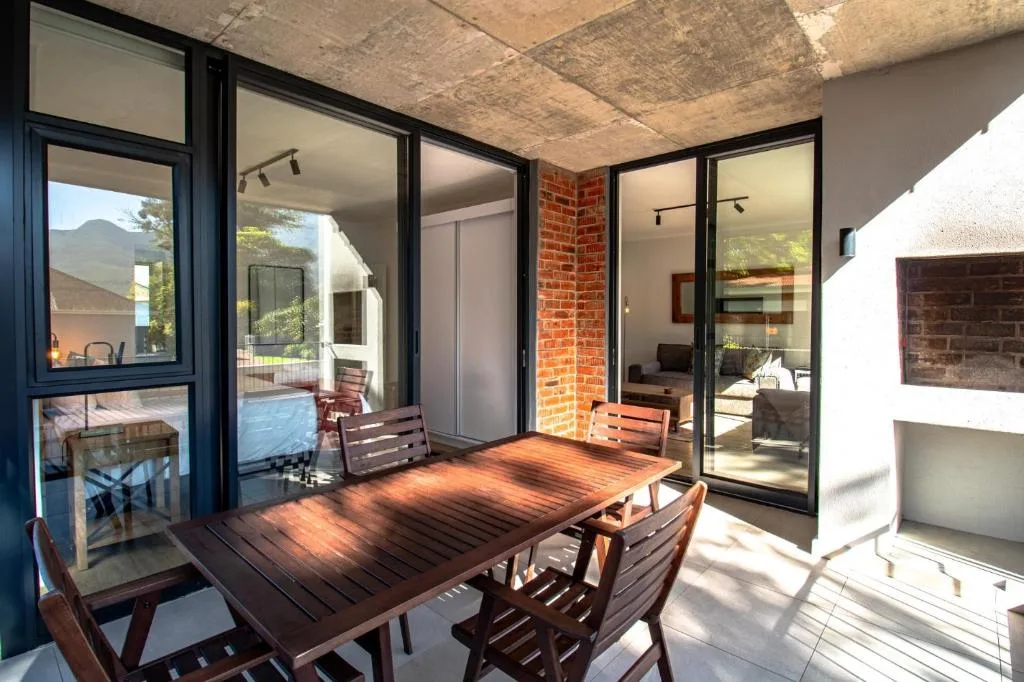 Wooden deck with dining table and chairs overlooking garden and mountains