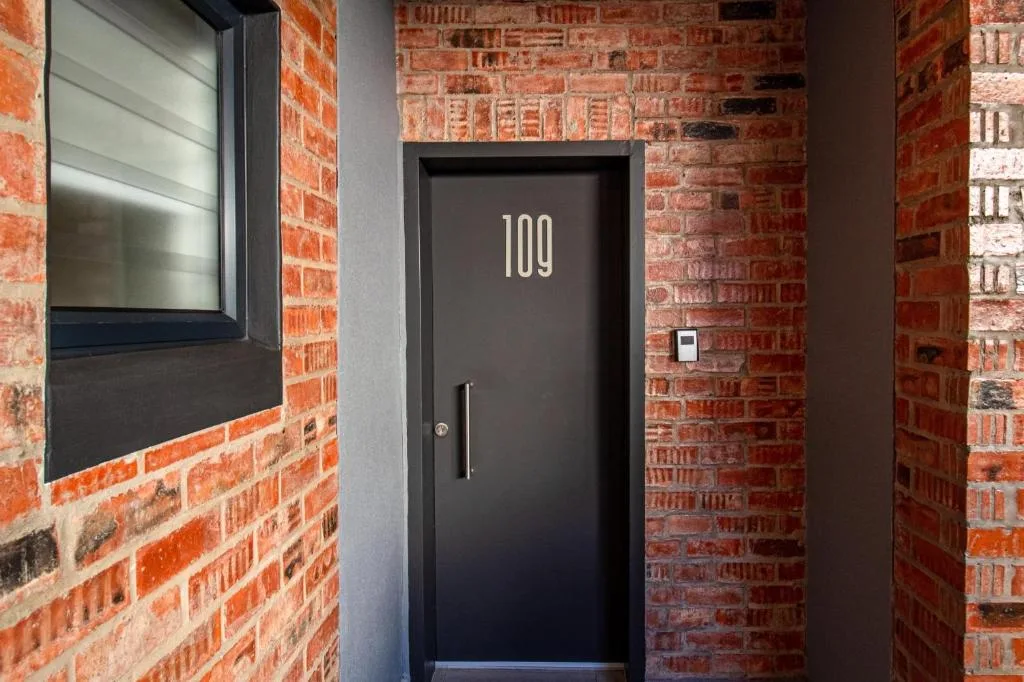 Modern black entrance door numbered 109 with brick facade