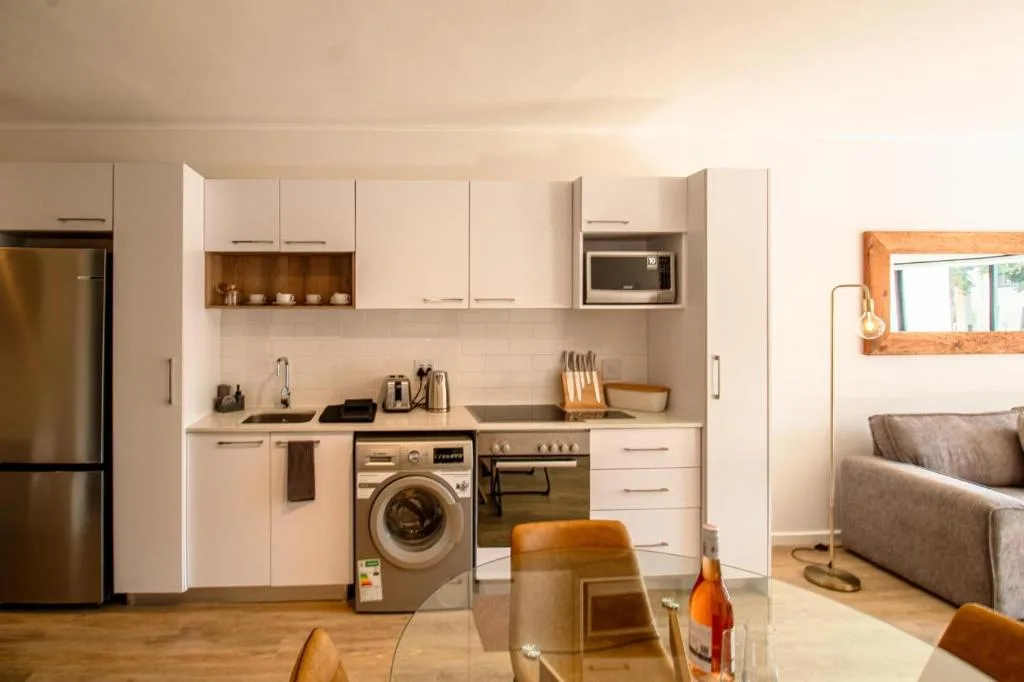 Modern kitchen with white cabinetry, stainless steel appliances, and integrated washing machine