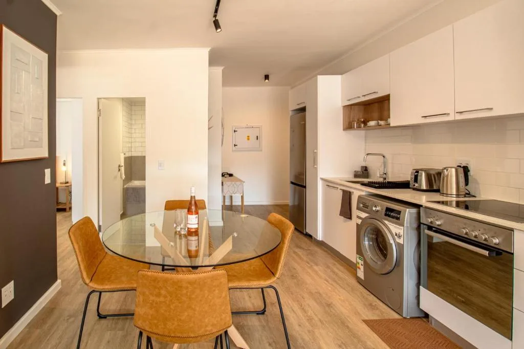 Modern kitchen with dining area, stainless steel appliances, white cabinetry