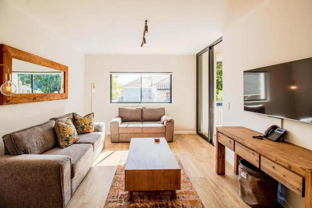 Spacious lounge with two sofas, TV, wooden furniture, and natural light