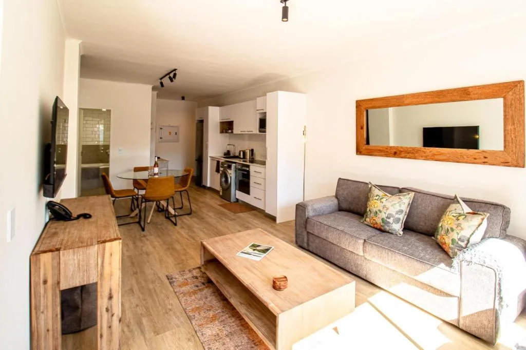 Open-plan living room with gray sofa, wooden coffee table, and wall mirror