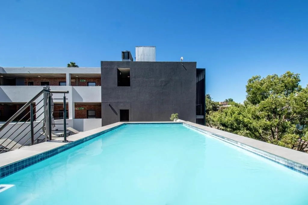 Large outdoor swimming pool with modern apartment building and garden views