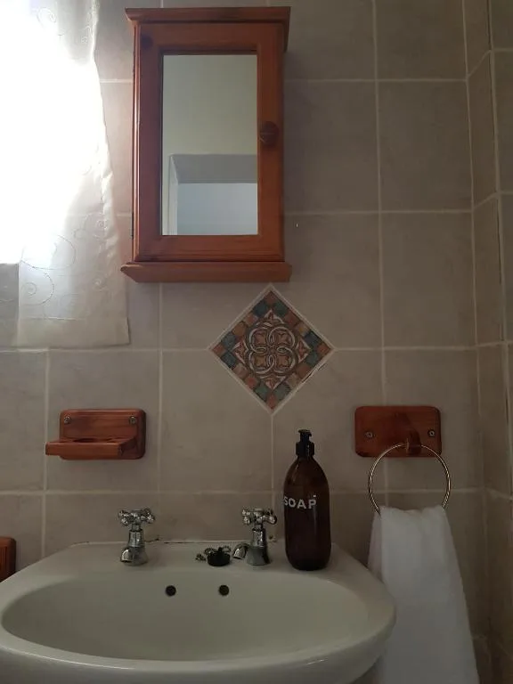 Bathroom vanity with round sink, mirror, and decorative tile details