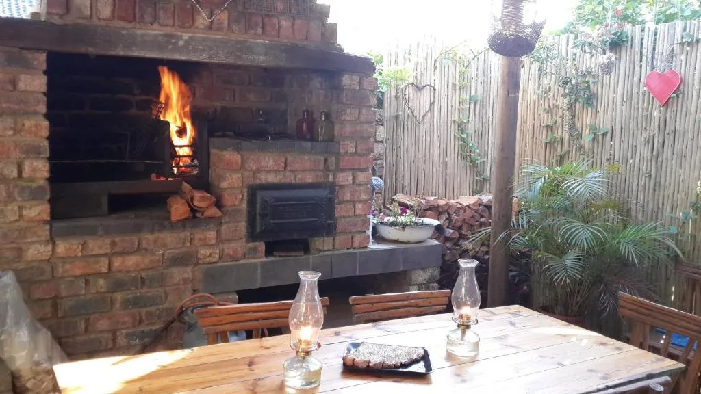 Outdoor braai area with active fireplace and wooden dining table setup