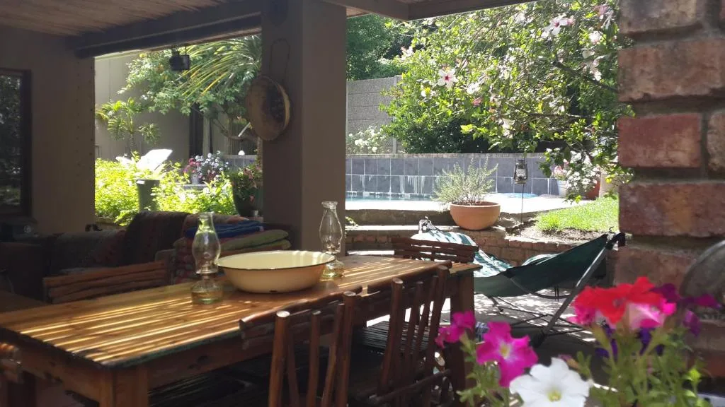 Covered outdoor patio with wooden dining table and lush garden views