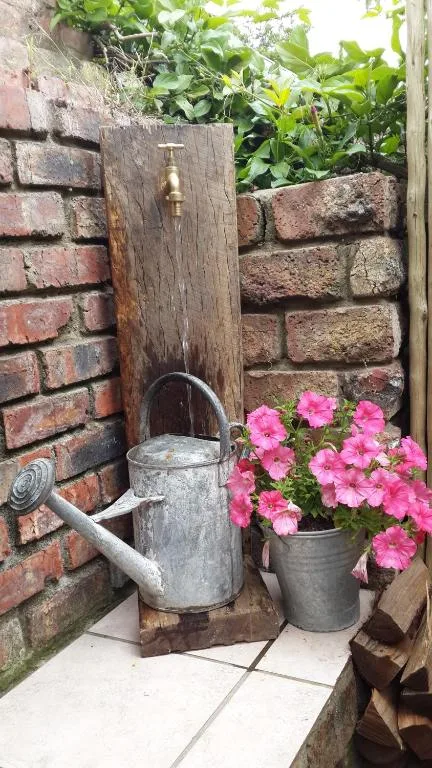 Rustic outdoor water feature with brass tap and flowering pink petunias