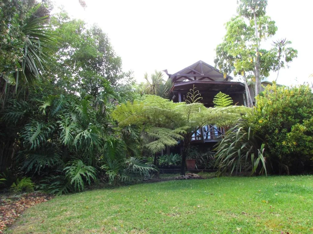 Lush garden surrounds dark timber cottage with verdant landscaping and lawn